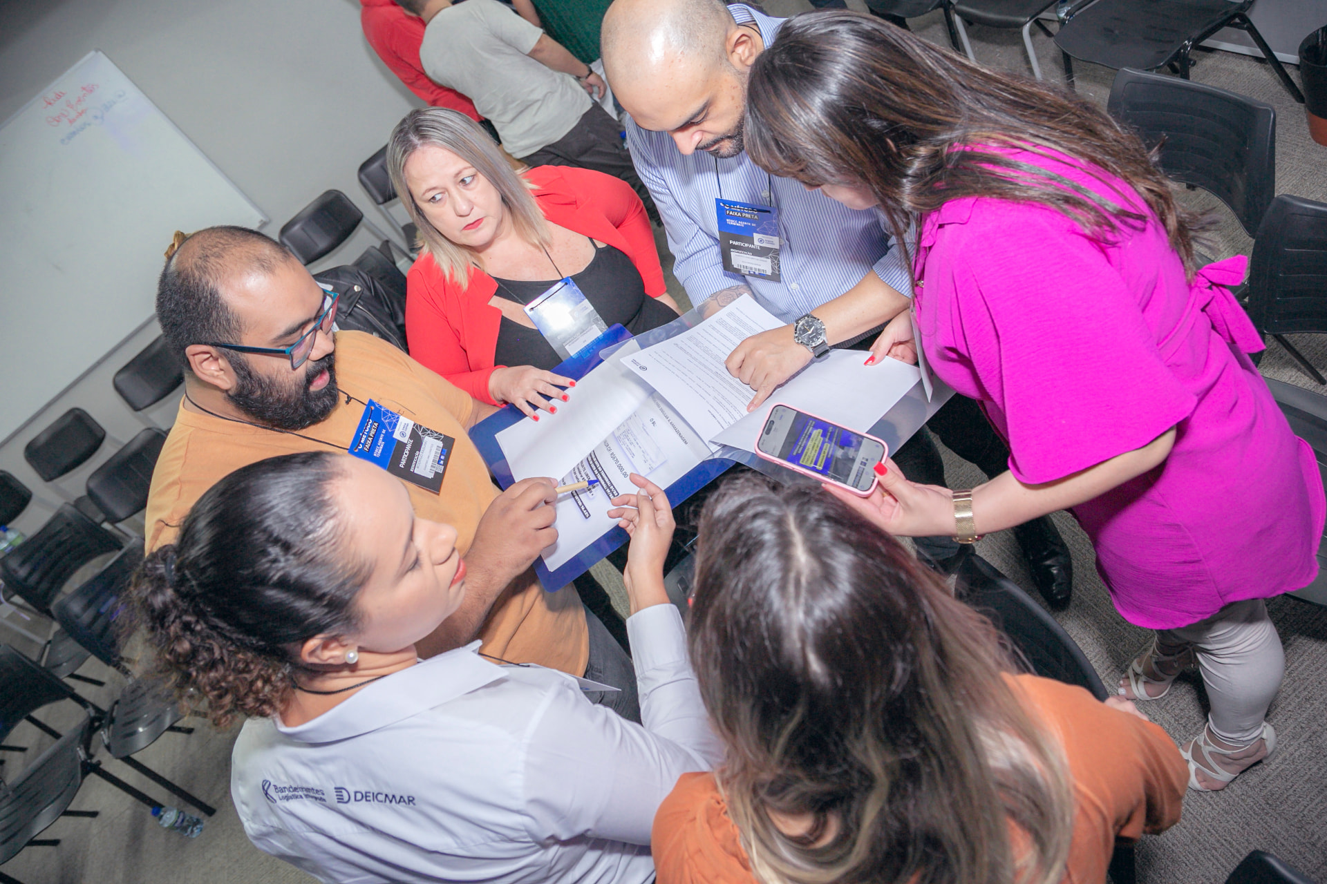 Alunos discutindo documentos em pasta azul durante treinamento